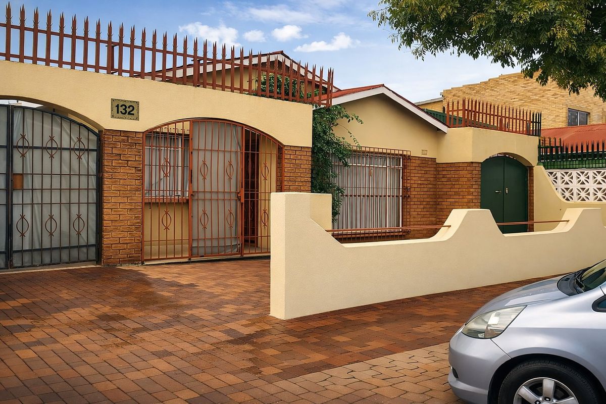 Front elevation of a residential property featuring a brick facade, secure gated entrance, and a paved driveway.