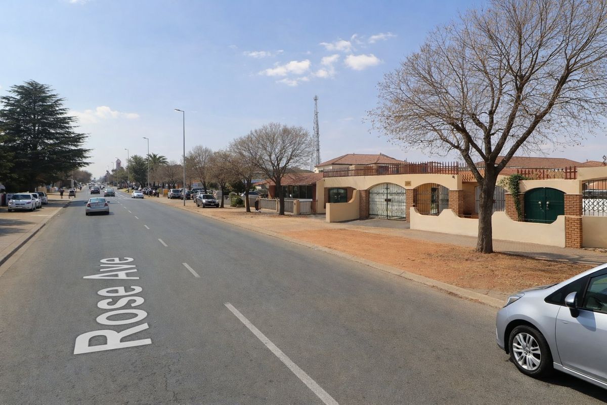 A street view of Rose Avenue showing the property's exterior boundary wall, security gate, and surrounding neighbourhood infrastructure.