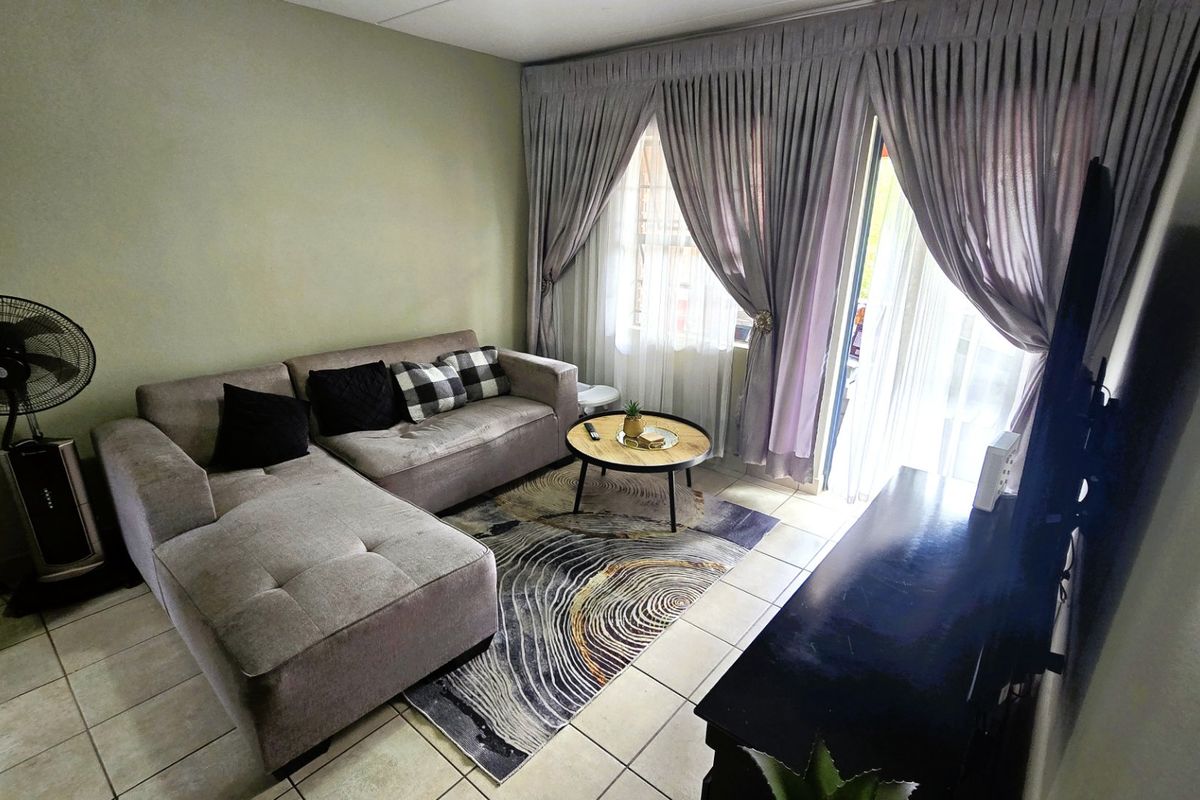 A comfortable living room featuring tiled flooring and a large sliding glass door that provides access to the outdoor area.