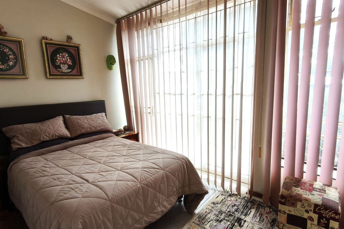 A bedroom featuring large sliding glass doors with vertical blinds, providing natural light and access to an outdoor area.