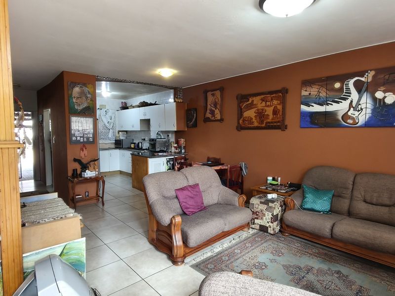 Open plan living area featuring tiled floors and a connected kitchen space with built-in cabinetry.