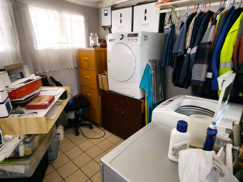 A functional laundry room featuring tiled floors, built-in cabinetry, and integrated power backup systems including an inverter and battery storage.