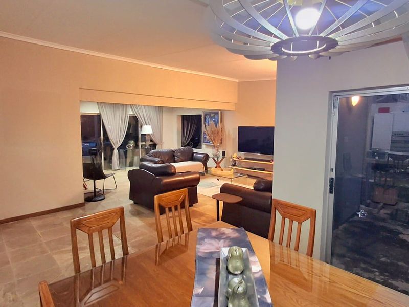 Spacious open-plan living and dining area featuring tiled flooring, large sliding glass doors, and modern lighting fixtures, creating a versatile and connected living space.