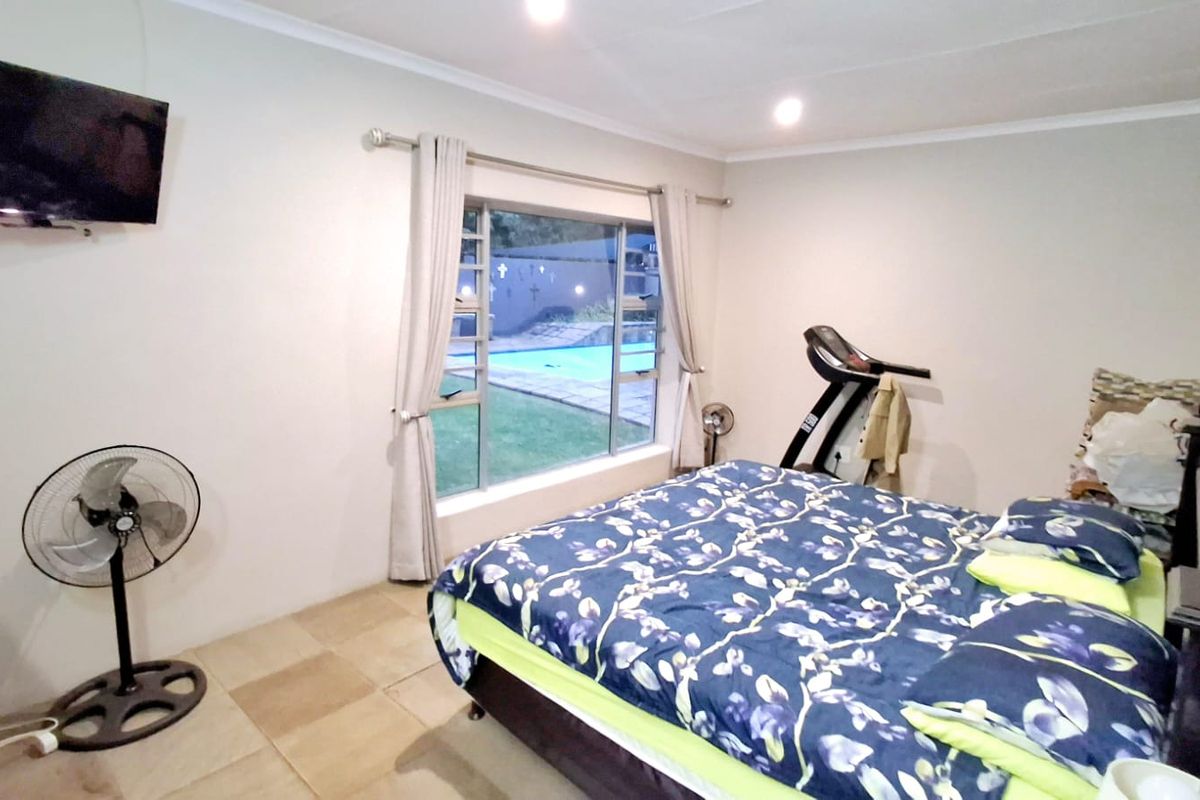 A bedroom featuring tiled flooring, recessed lighting, and a large window with views of the outdoor pool area.