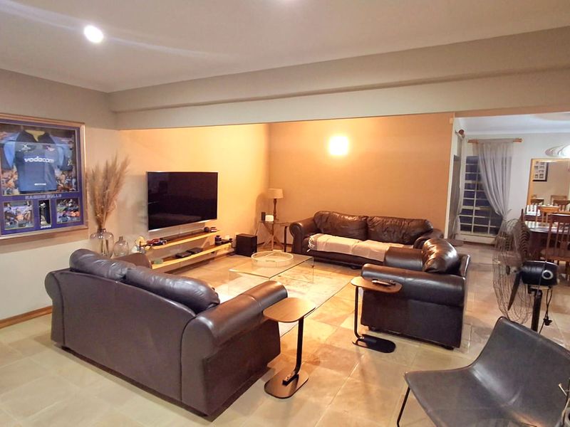 Spacious open-plan living area featuring tiled flooring, recessed downlighting, and a bulkhead ceiling, seamlessly connecting to the adjacent dining space.