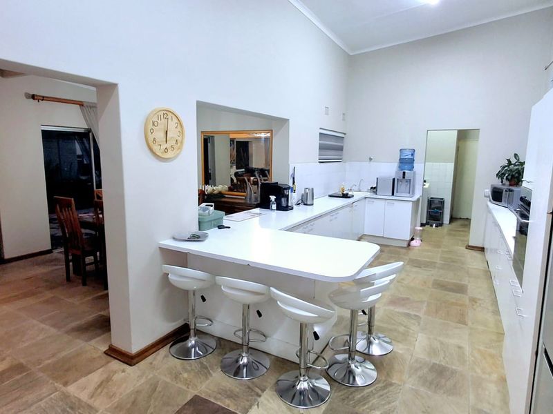 Open plan kitchen featuring a breakfast bar, ample built-in cabinetry, and tiled flooring, seamlessly connecting to the adjacent living and dining areas.
