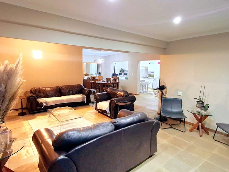Spacious open-plan living area featuring neutral walls, tiled flooring, and recessed lighting, seamlessly connecting to the dining and kitchen spaces.