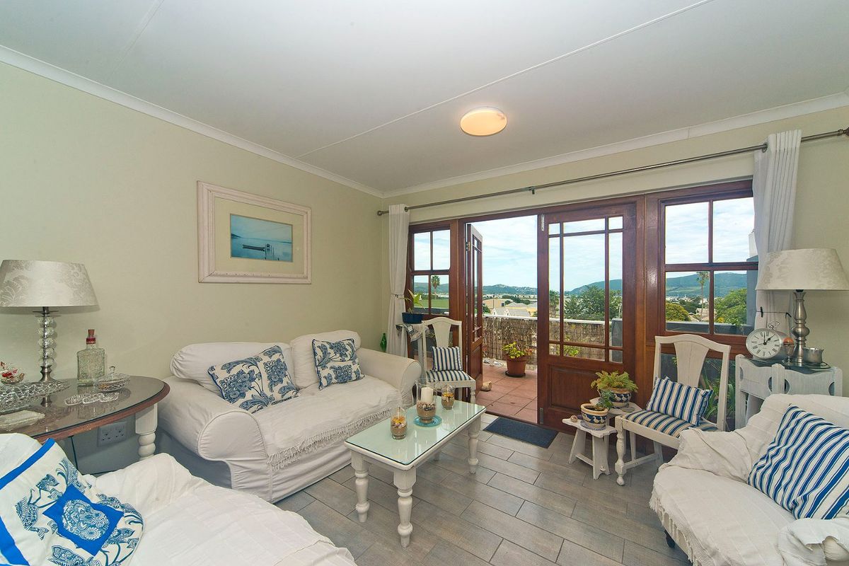 A comfortable living room featuring tiled floors and timber-framed glass doors that open onto a balcony with scenic views.