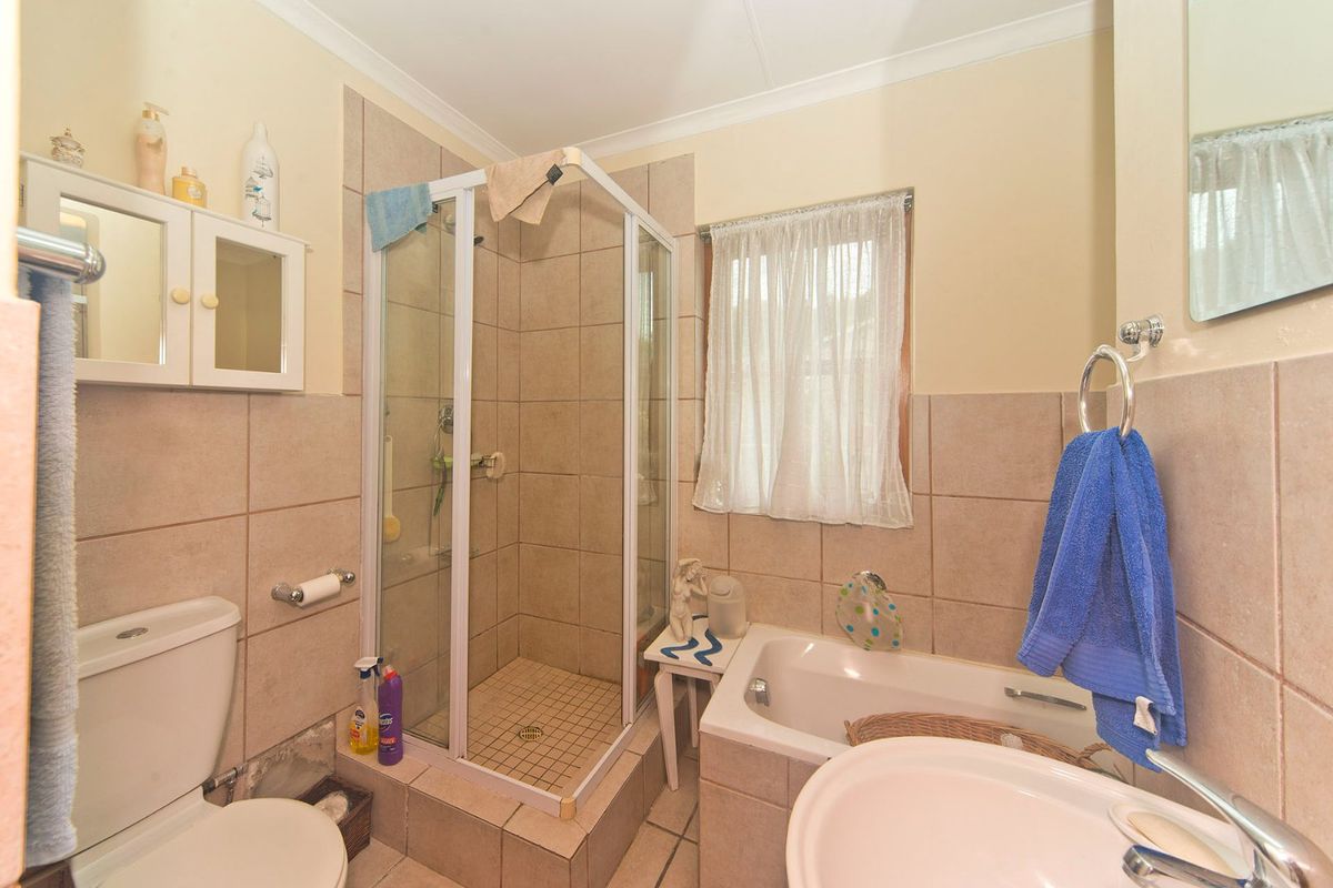 A functional bathroom featuring a separate shower enclosure, built-in bathtub, pedestal basin, and neutral ceramic tiling throughout.