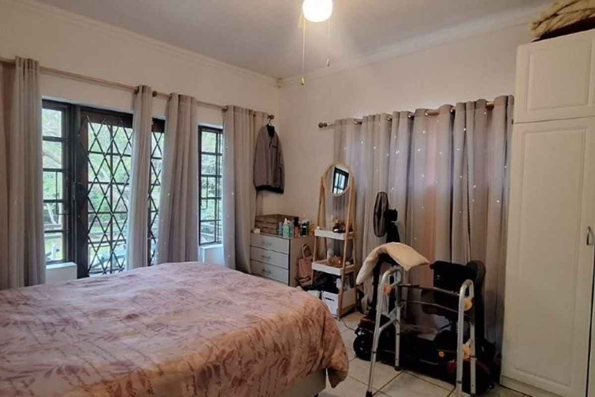 A bedroom featuring tiled flooring, a built-in wardrobe, and a security gate leading to the exterior.
