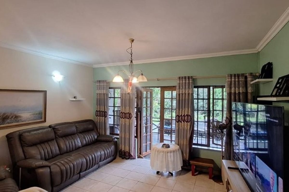 A comfortable living room featuring tiled flooring, coving, and direct access to an outdoor patio through classic french doors.