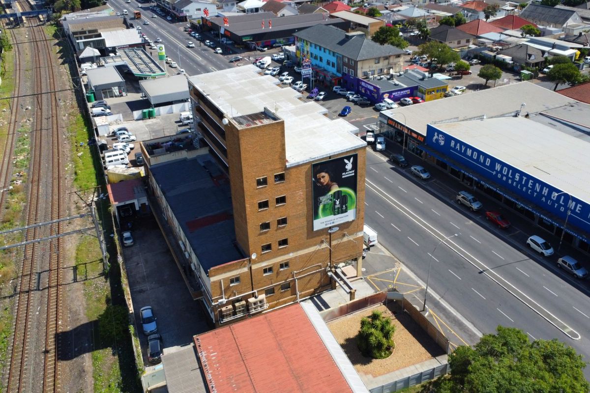 Aerial view of a multi-story commercial building featuring a brick facade, flat roof, and prominent external advertising billboard situated in a busy urban area.