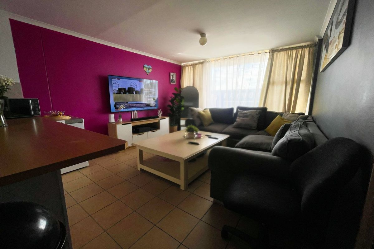 A living room area featuring tiled flooring and a bold accent wall, providing a functional space for relaxation.