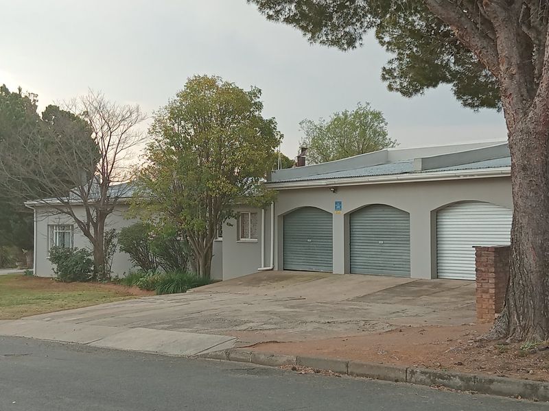 Front view of the property featuring a triple garage with roller shutter doors and a concrete driveway.