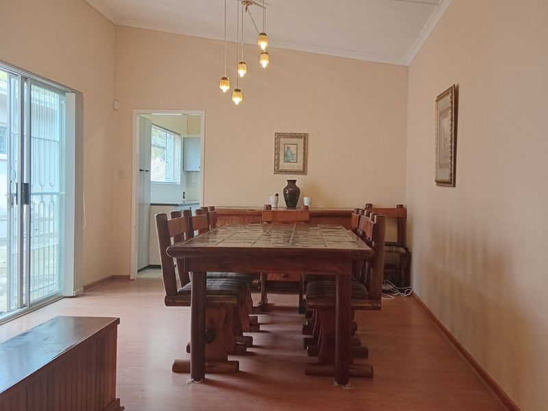 A dining room featuring laminate flooring, a raised platform area, and a sliding glass door providing access to the exterior.