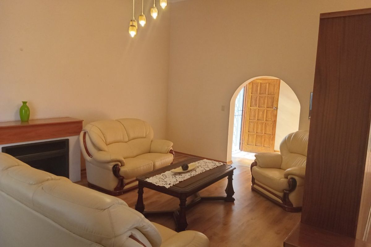 A living room featuring laminate flooring, a fireplace, and an arched doorway leading to an entrance.