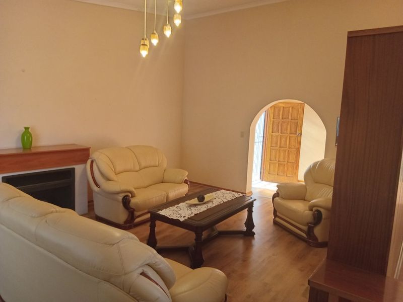 A living room featuring laminate flooring, a fireplace, and an arched doorway leading to an entrance.