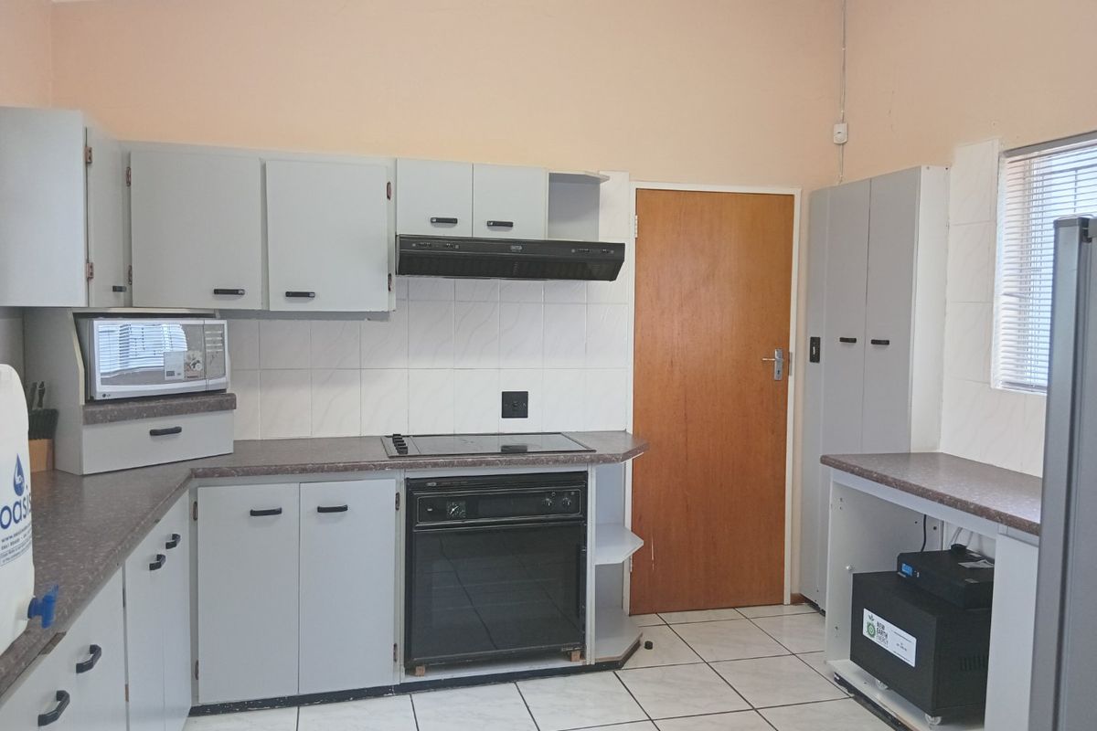 Functional kitchen featuring built-in cabinetry, laminate countertops, integrated oven and hob, and ceramic floor tiles, offering a practical layout for daily use.