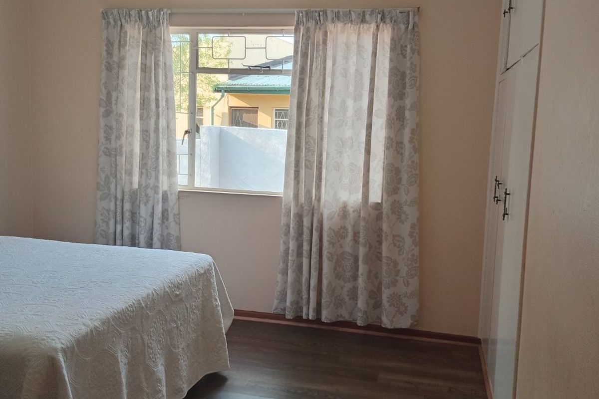 A well-maintained bedroom featuring laminate flooring and built-in cupboards, offering a clean and functional living space.