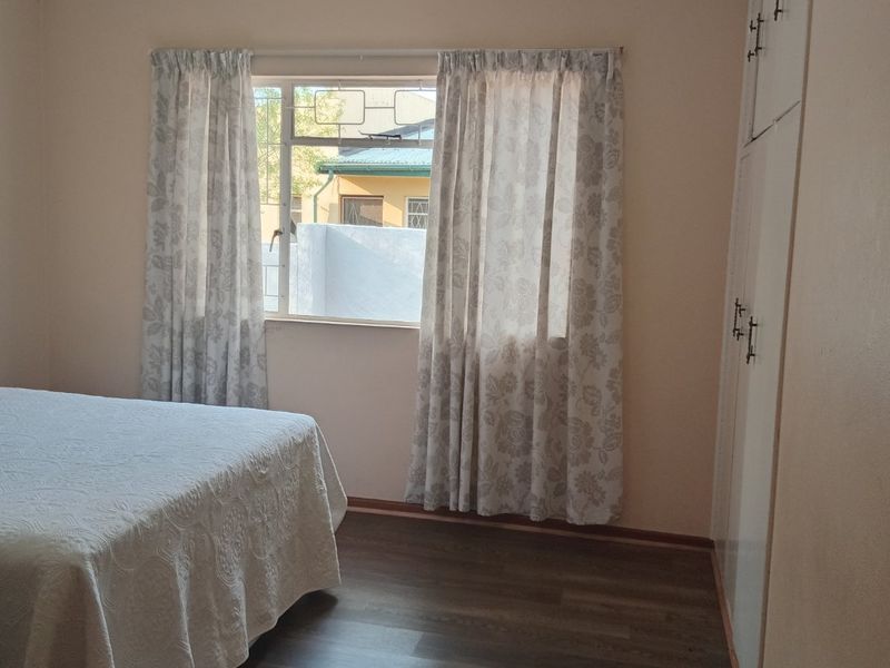 A well-maintained bedroom featuring laminate flooring and built-in cupboards, offering a clean and functional living space.