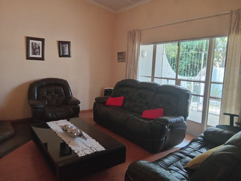 A living room featuring laminate flooring and a large sliding glass door with an integrated security gate, providing access to the outdoor area.