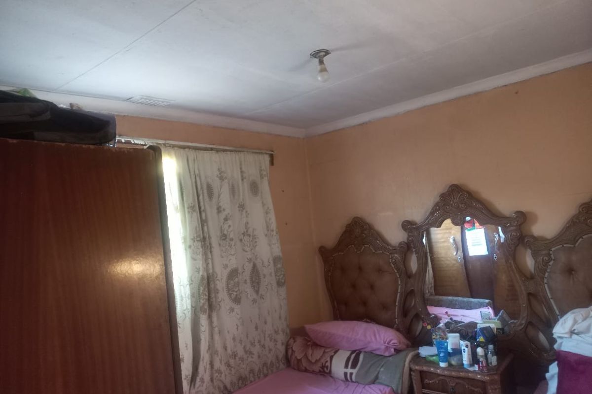 A bedroom featuring basic finishes, including a window with curtains and a central ceiling light fixture.