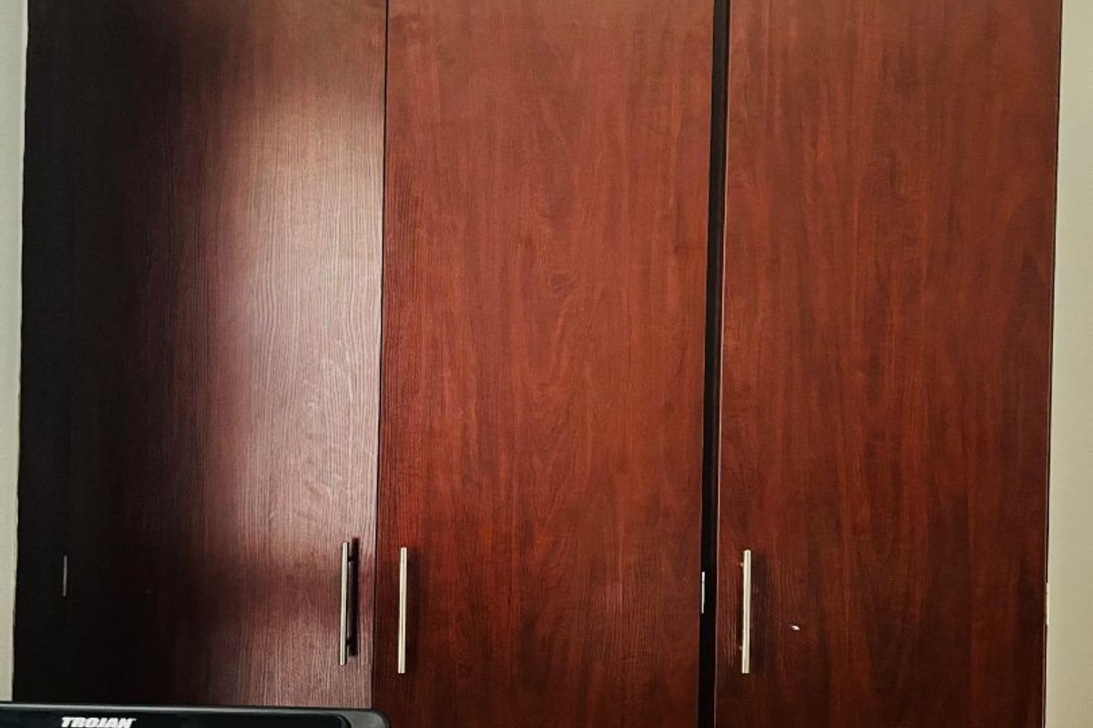 A bedroom featuring dark wood-finish built-in cupboards with modern metal handles.