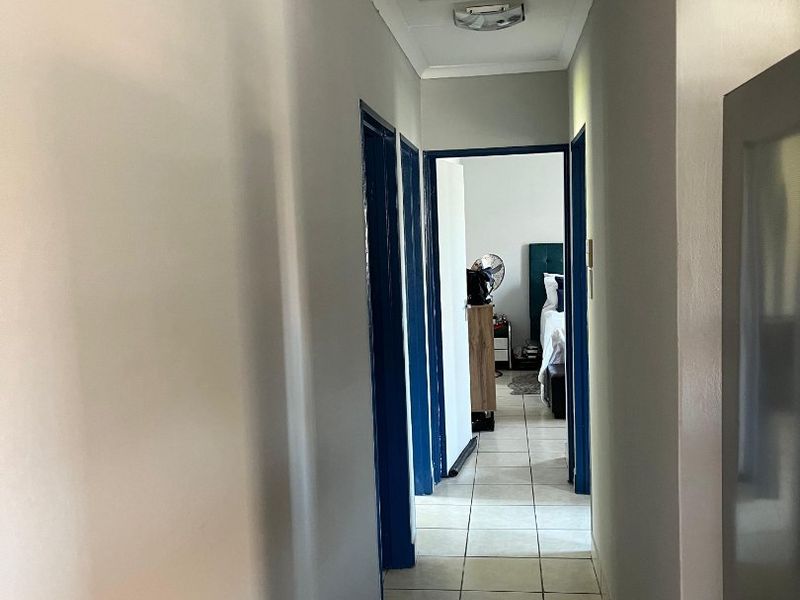 A clean, tiled hallway providing access to adjacent rooms, featuring neutral wall finishes and a ceiling access hatch.