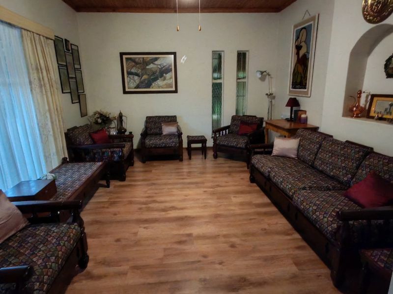 A living room featuring a warm timber ceiling, ceiling fan, and laminate flooring, complemented by an arched wall niche and vertical windows.