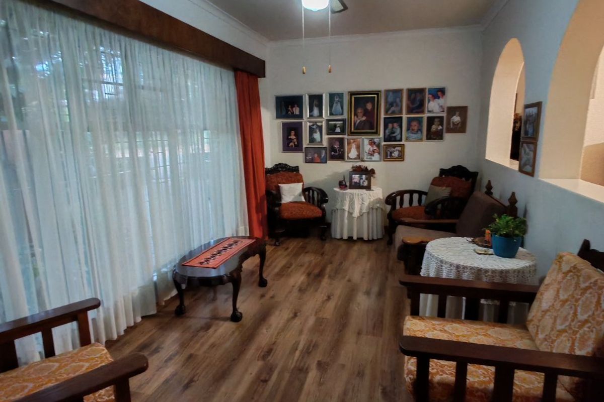A cozy living room featuring laminate flooring, a ceiling fan, and distinctive architectural archways, providing a warm and inviting atmosphere.
