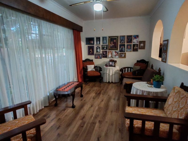 A cozy living room featuring laminate flooring, a ceiling fan, and distinctive architectural archways, providing a warm and inviting atmosphere.