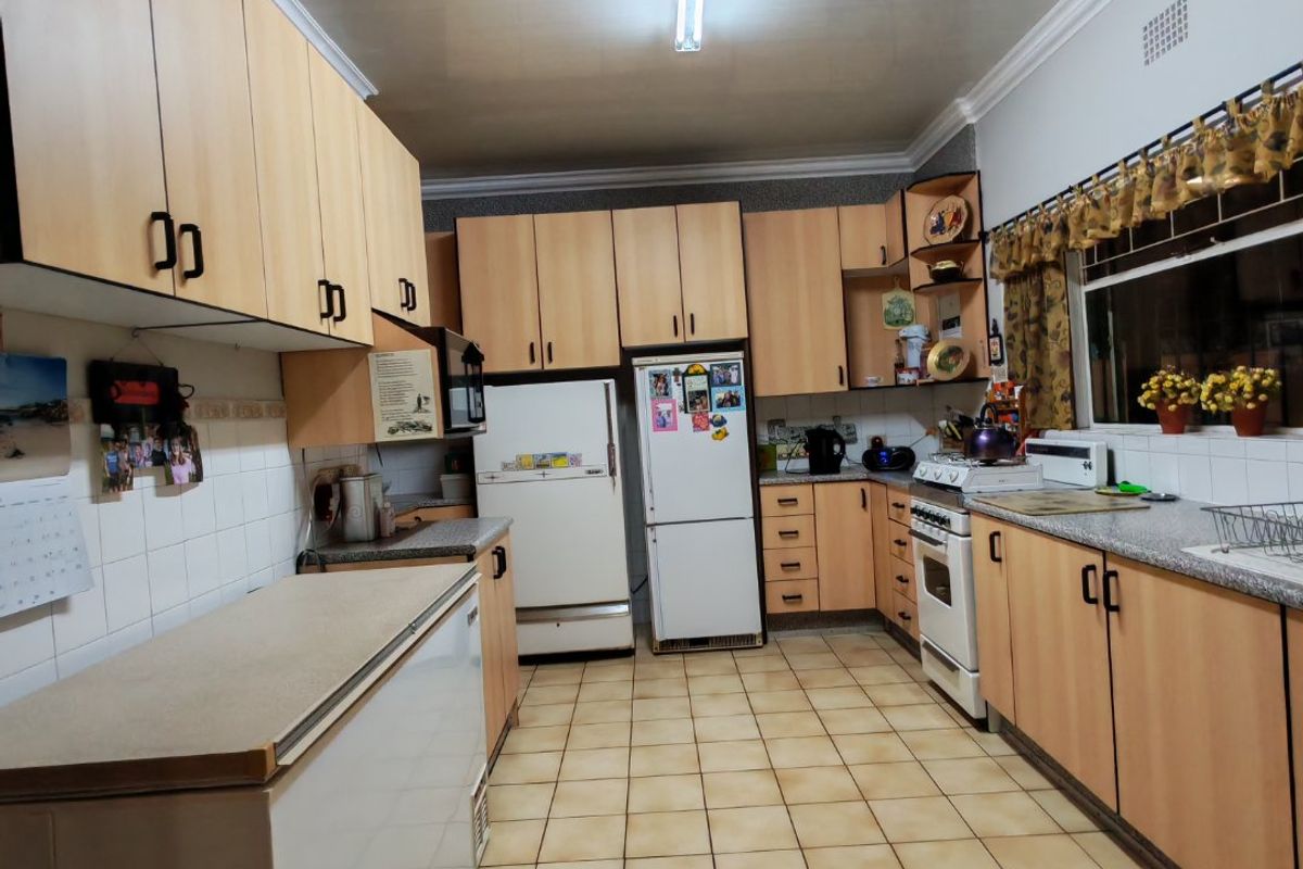 A functional kitchen featuring light wood-tone cabinetry, granite countertops, ceramic tile flooring, and a classic freestanding oven, offering a practical layout for daily use.