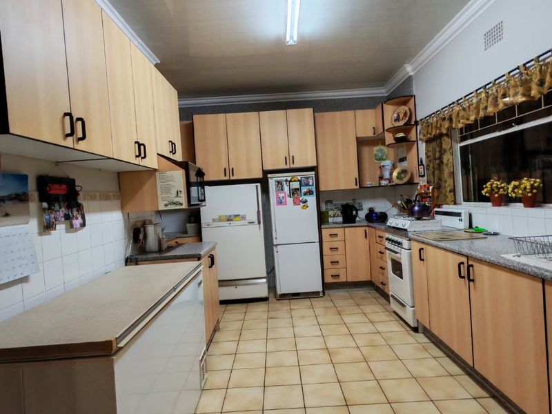A functional kitchen featuring light wood-tone cabinetry, granite countertops, ceramic tile flooring, and a classic freestanding oven, offering a practical layout for daily use.