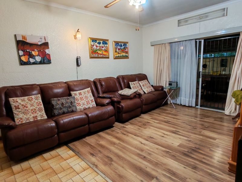 Living room featuring a ceiling fan, mixed laminate and tiled flooring, and sliding glass doors leading to an outdoor area with security gate.