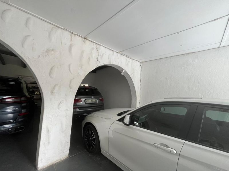 A functional garage space featuring distinctive arched masonry pillars and concrete flooring, showing signs of wear and cracking on the structural plasterwork.