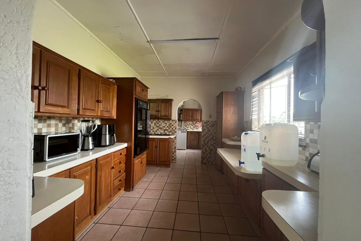 A dated kitchen featuring extensive wooden cabinetry, tiled backsplash, and tiled flooring, offering a functional layout with potential for modern renovation.
