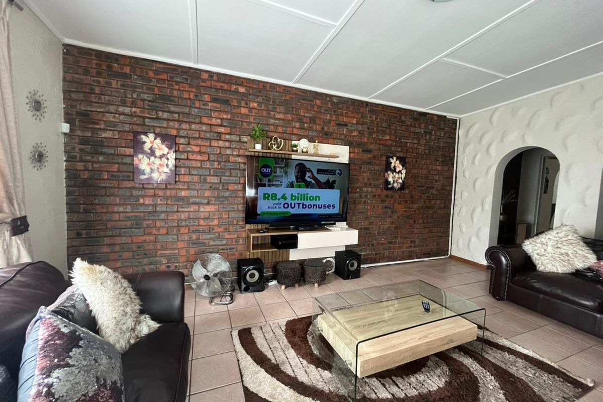 Living room featuring an exposed brick feature wall, textured accent wall, tiled flooring, and an arched entryway.