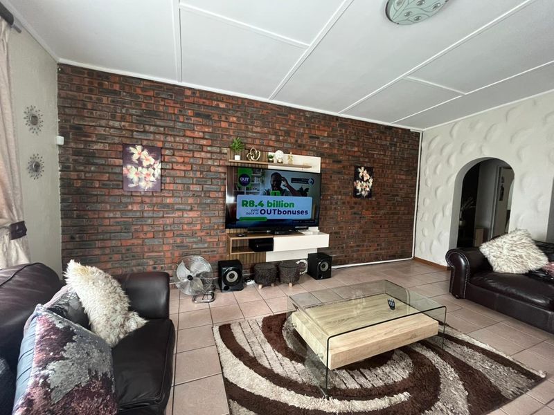 Living room featuring an exposed brick feature wall, textured accent wall, tiled flooring, and an arched entryway.