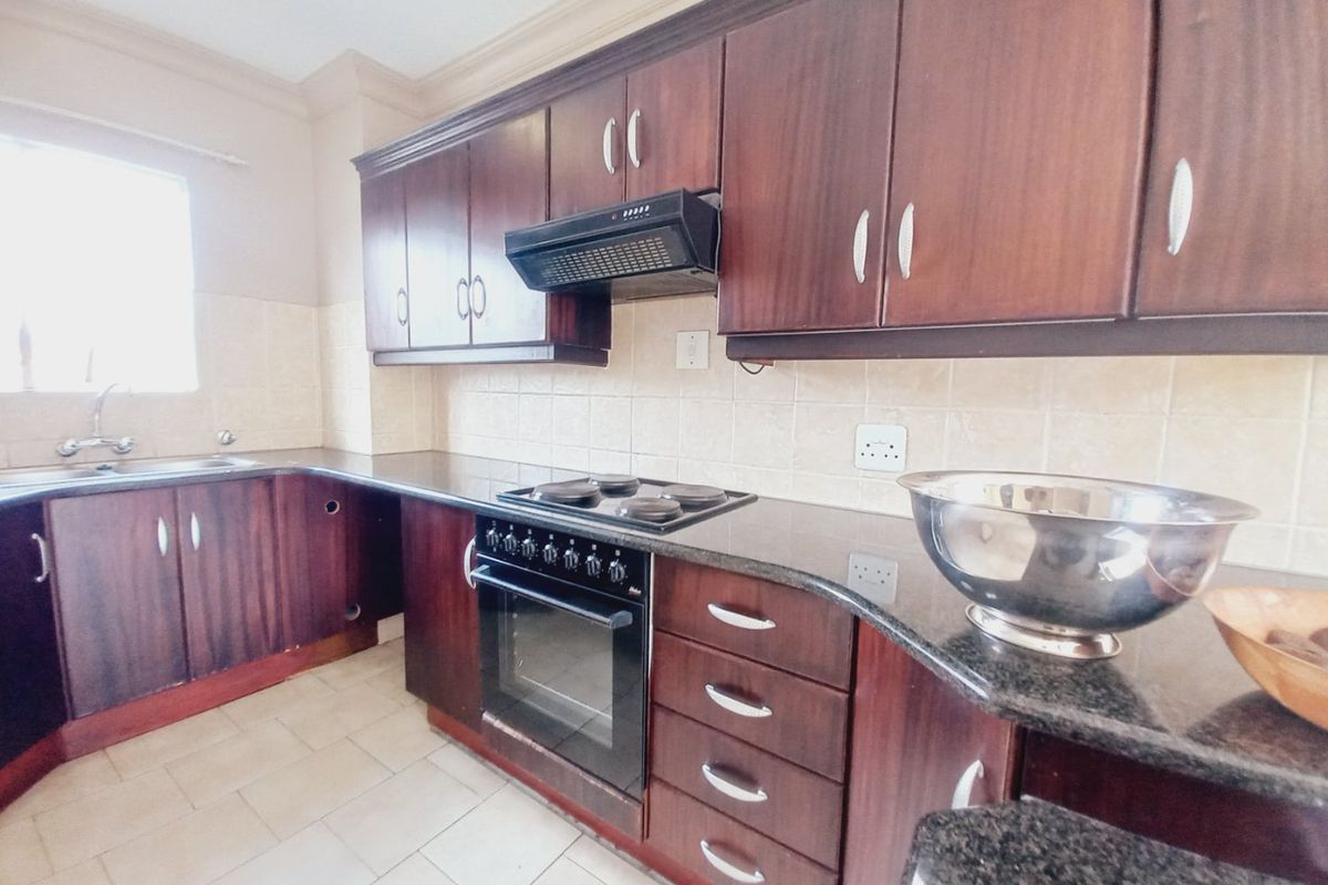 A functional kitchen featuring dark wood cabinetry, granite countertops, built-in oven, and hob, with a tiled backsplash and ceramic flooring.