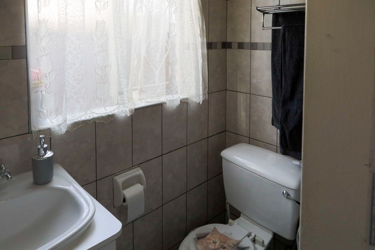 A functional bathroom featuring neutral ceramic wall tiles, a pedestal washbasin, and a standard toilet with a wall-mounted towel rail.