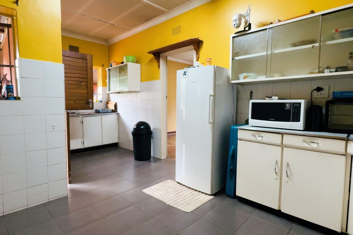 A functional kitchen featuring tiled splashbacks, built-in cabinetry, and tiled flooring, offering a dated aesthetic with potential for modernization.
