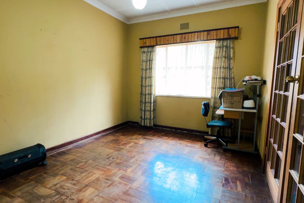 A bedroom featuring original parquet flooring, timber-framed glass panel doors, and classic cornicing, offering a solid foundation for renovation or modernization.