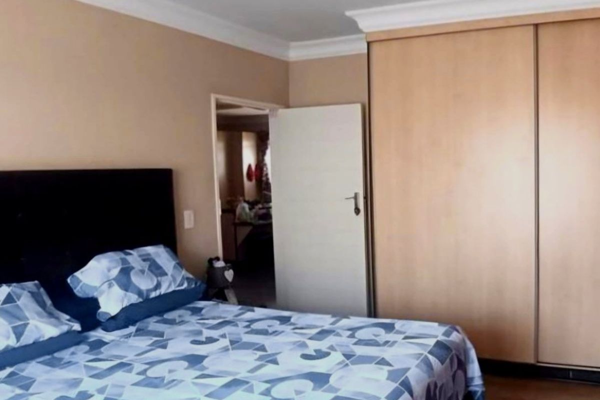 A bedroom featuring a large built-in wardrobe with sliding doors and decorative ceiling coving.