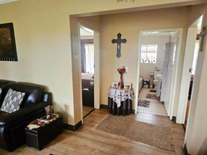 A living area featuring laminate flooring and coving, providing access to adjacent rooms including a bathroom.