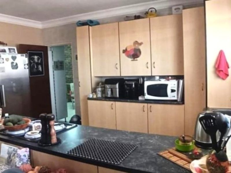 Functional kitchen featuring laminate cabinetry, dark countertops, and a built-in hob, offering a practical layout for daily meal preparation.