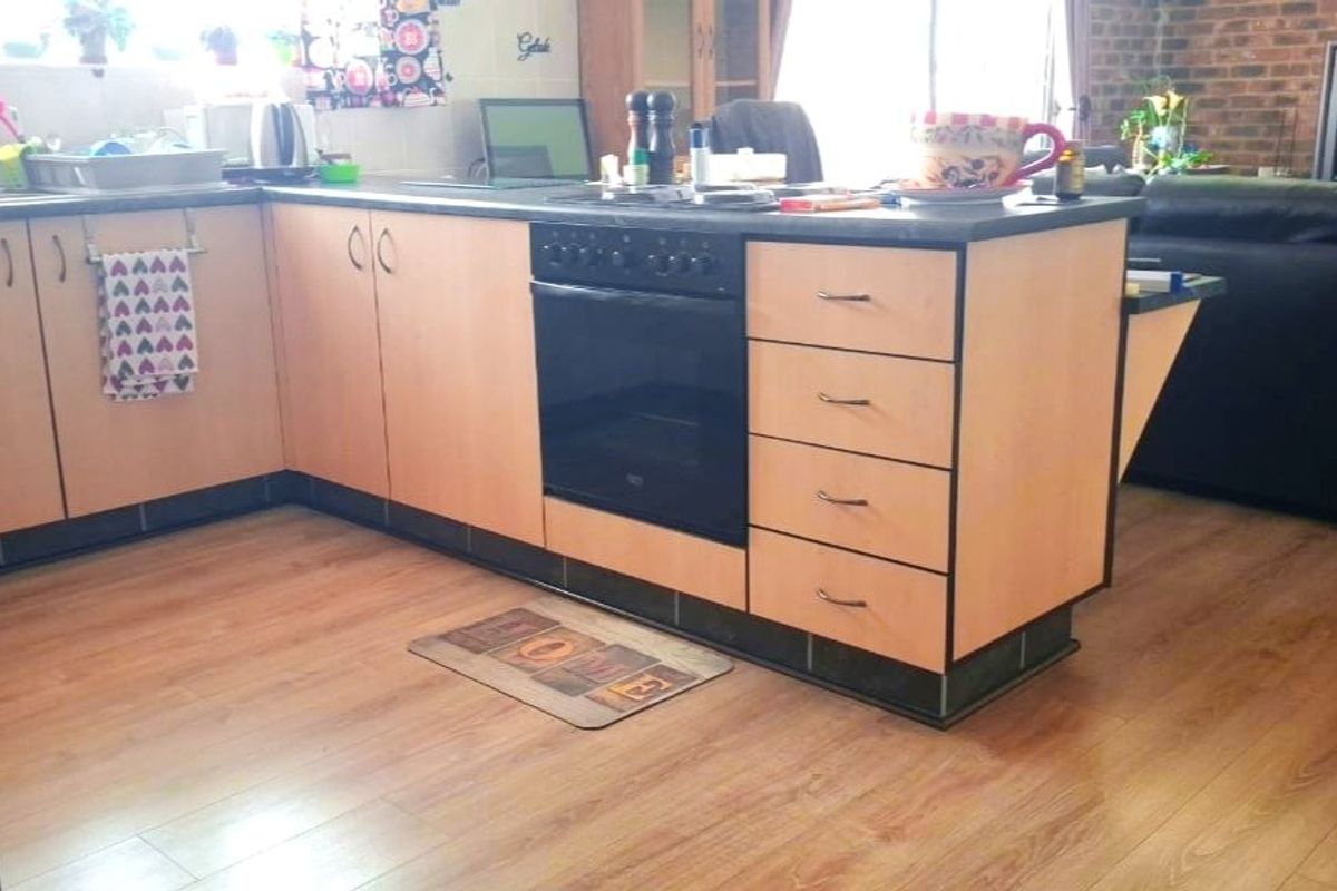 A functional kitchen featuring light wood-tone cabinetry, a built-in oven, and durable laminate flooring, offering a practical layout for daily meal preparation.