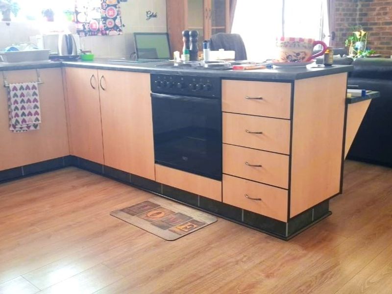 A functional kitchen featuring light wood-tone cabinetry, a built-in oven, and durable laminate flooring, offering a practical layout for daily meal preparation.
