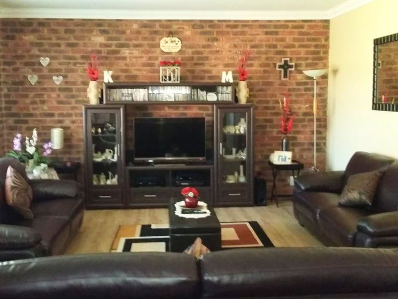 A living room featuring an exposed brick feature wall, laminate flooring, and coved ceiling details.