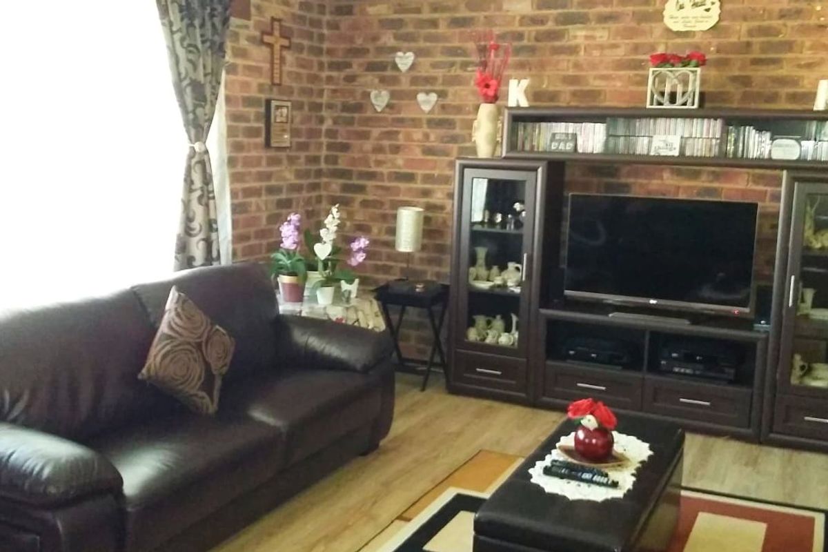 A living room featuring an exposed brick feature wall and laminate flooring, providing a warm and textured aesthetic.