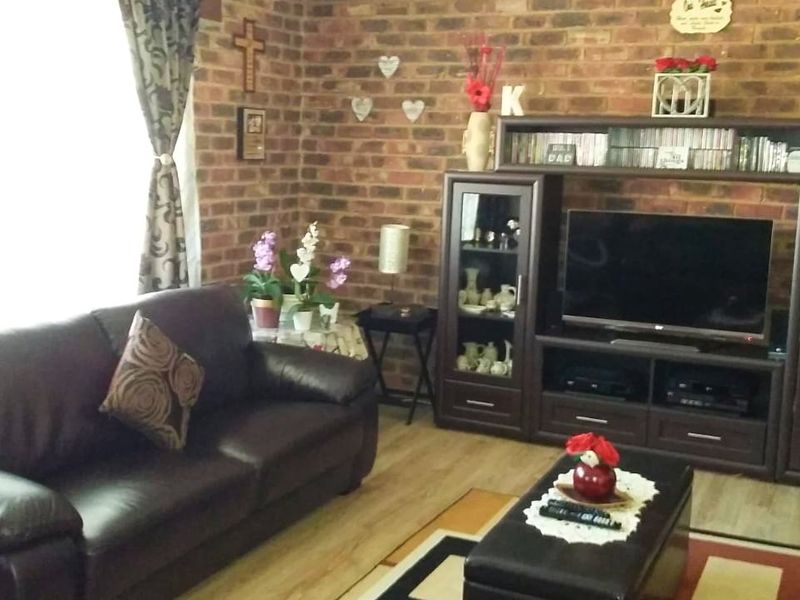 A living room featuring an exposed brick feature wall and laminate flooring, providing a warm and textured aesthetic.